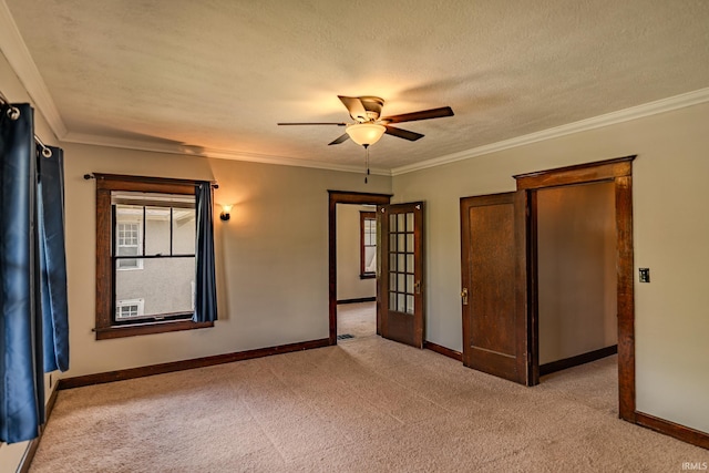 empty room featuring a ceiling fan, baseboards, light colored carpet, and ornamental molding