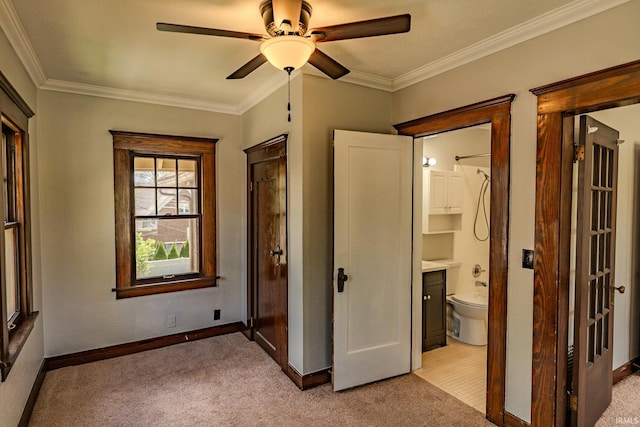 unfurnished bedroom featuring ornamental molding, baseboards, ceiling fan, light colored carpet, and connected bathroom
