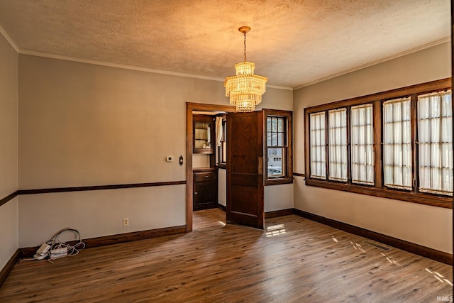 spare room featuring baseboards, a notable chandelier, a textured ceiling, and dark wood-type flooring
