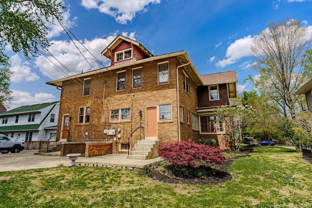 rear view of house featuring a yard, brick siding, and entry steps