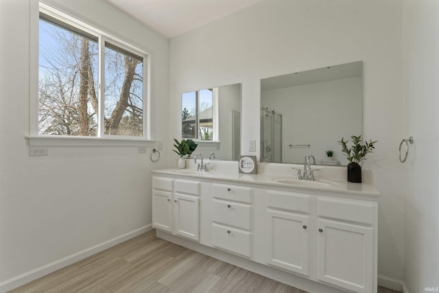 full bathroom featuring double vanity, baseboards, a sink, and wood finished floors