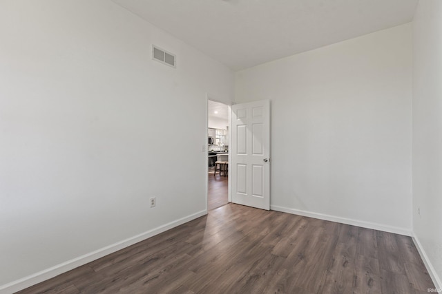 spare room with baseboards, dark wood-style floors, and visible vents