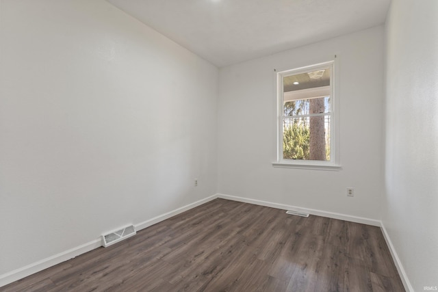 empty room featuring baseboards, dark wood-type flooring, and visible vents