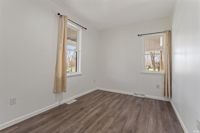 unfurnished room with baseboards, dark wood-style flooring, and visible vents