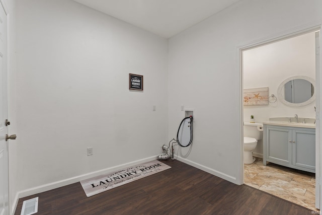 washroom with visible vents, dark wood-style flooring, baseboards, hookup for a washing machine, and a sink