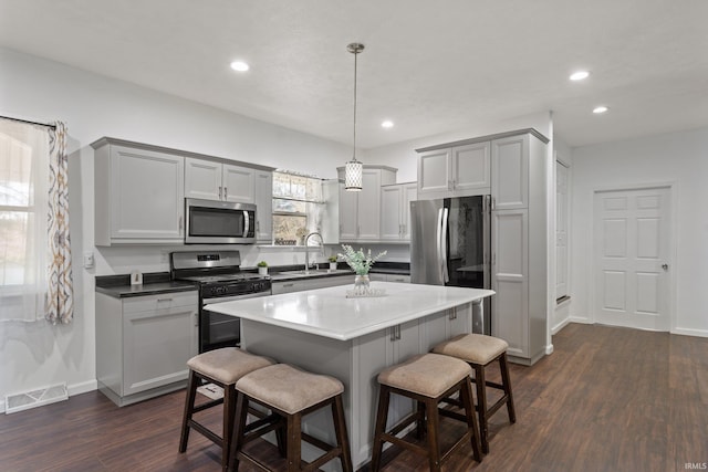 kitchen featuring a breakfast bar area, dark wood-style flooring, a sink, stainless steel appliances, and recessed lighting