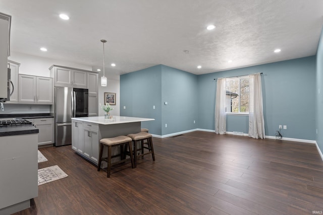 kitchen with baseboards, freestanding refrigerator, a kitchen island, and recessed lighting
