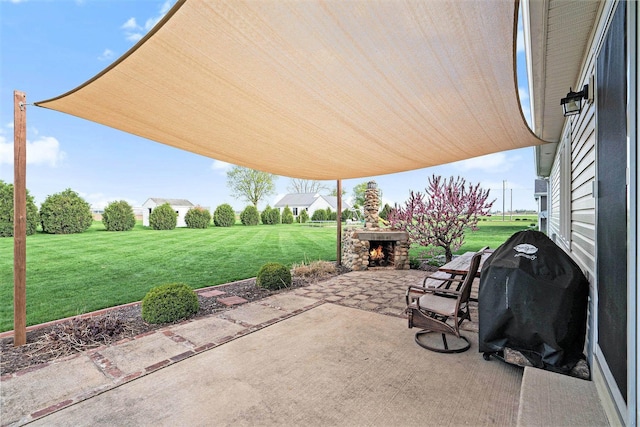 view of patio with an outdoor stone fireplace and a grill