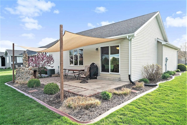 rear view of property with a lawn, roof with shingles, cooling unit, and a patio area