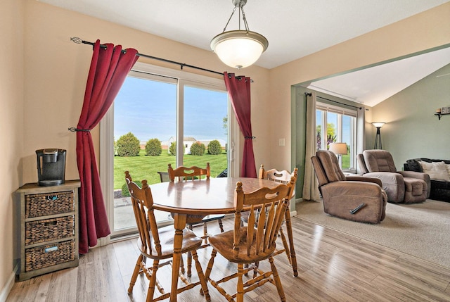 dining room with light wood-style floors and vaulted ceiling