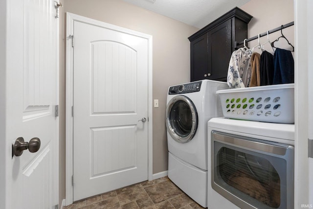 clothes washing area with cabinet space, separate washer and dryer, baseboards, and stone finish flooring