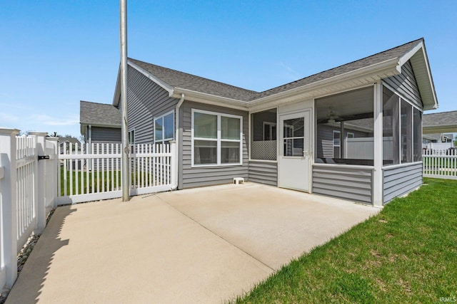 rear view of property featuring fence, roof with shingles, a sunroom, a patio area, and a yard