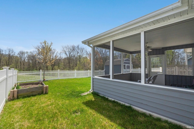 view of yard with a fenced backyard, ceiling fan, a vegetable garden, and a storage shed