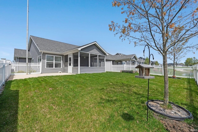 back of house featuring a fenced backyard, a yard, and a sunroom