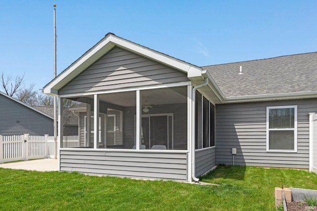 back of house with a lawn, fence, a shingled roof, and a sunroom