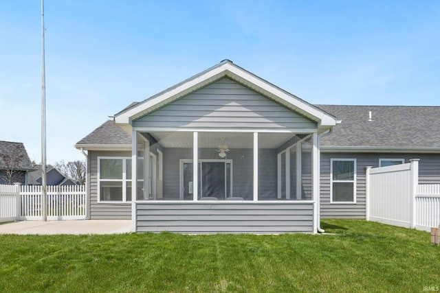 back of house featuring a yard, fence, a shingled roof, and a sunroom