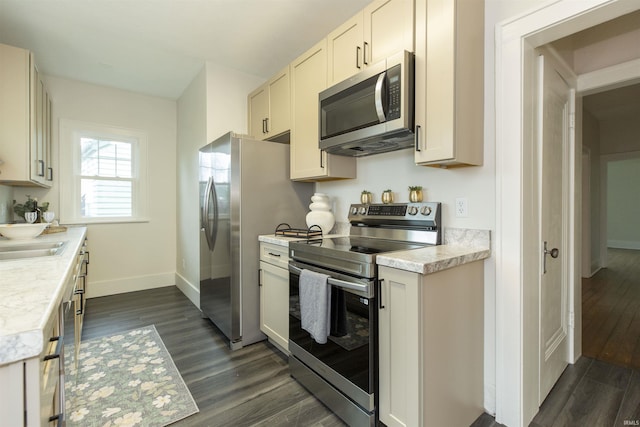 kitchen with baseboards, dark wood-style floors, light countertops, a sink, and stainless steel appliances