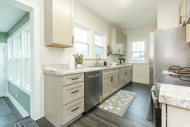 kitchen with light countertops, dark wood finished floors, a sink, and dishwasher