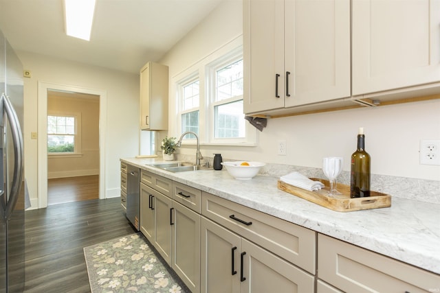 kitchen with light stone countertops, appliances with stainless steel finishes, a sink, baseboards, and dark wood-type flooring