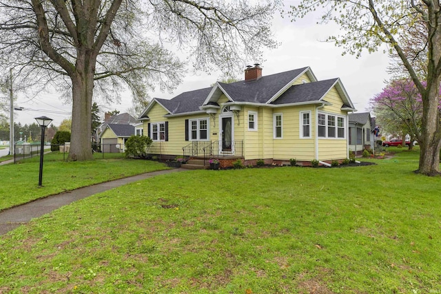 view of front of home featuring a front lawn, roof with shingles, fence, and a chimney