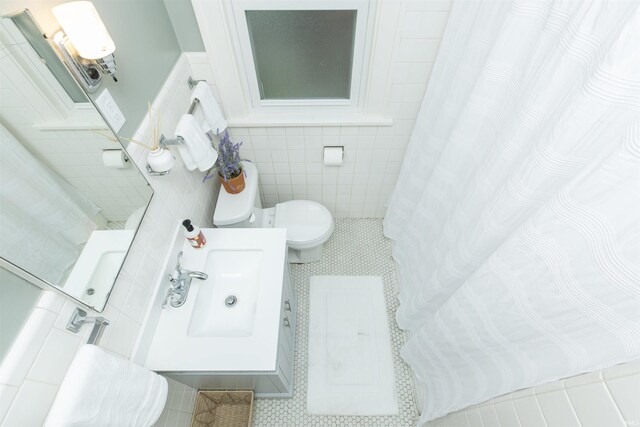 bathroom featuring tile patterned flooring, vanity, toilet, tile walls, and curtained shower