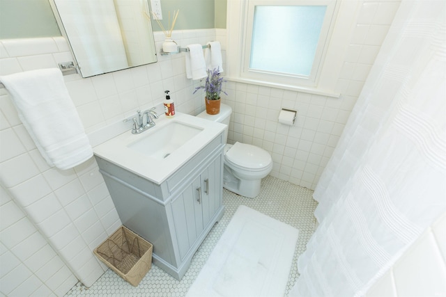 full bathroom with wainscoting, vanity, toilet, a shower with shower curtain, and tile walls