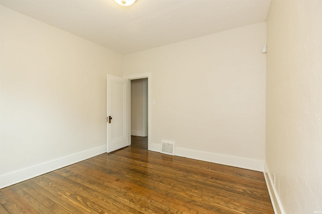 unfurnished room with baseboards, visible vents, and wood finished floors