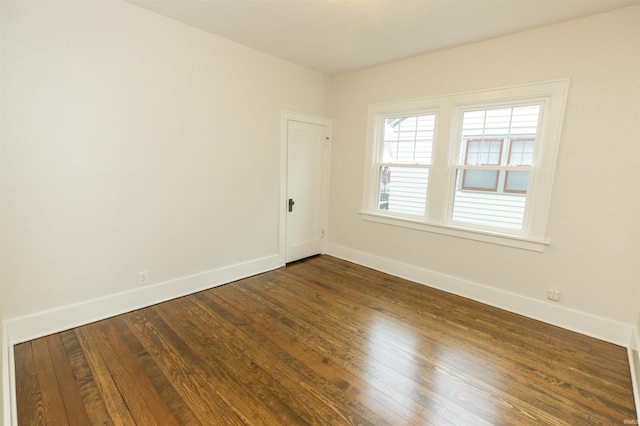 unfurnished room featuring baseboards and dark wood finished floors