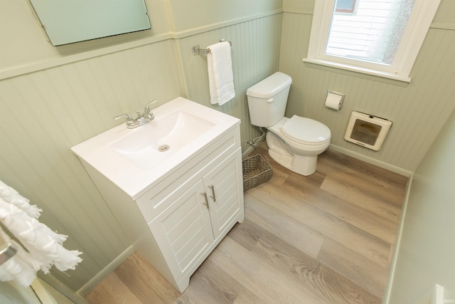 bathroom with toilet, heating unit, wood finished floors, and vanity