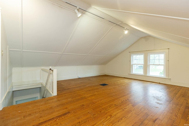 additional living space featuring baseboards, vaulted ceiling, wood finished floors, and visible vents