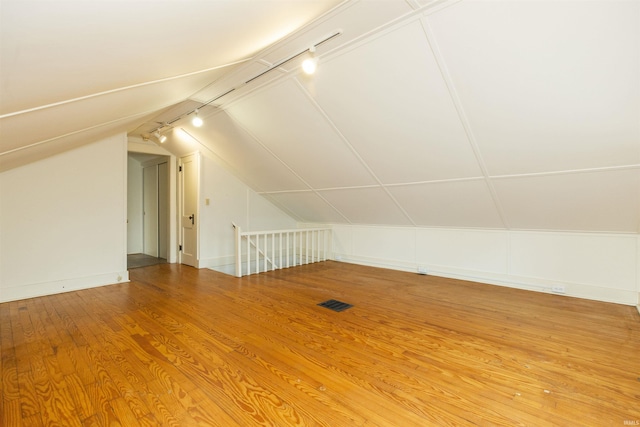 additional living space with visible vents, baseboards, lofted ceiling, and wood finished floors