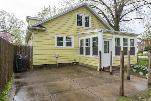 rear view of house featuring a sunroom, a patio area, and fence