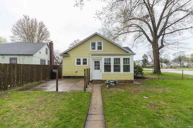 rear view of house with a yard, fence, and a patio area