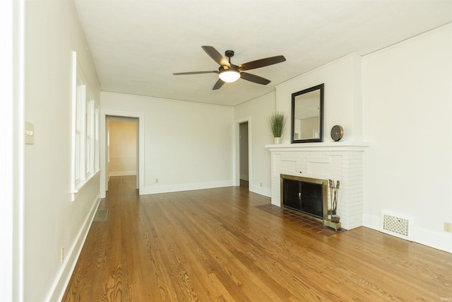 unfurnished living room featuring ceiling fan, a fireplace, wood finished floors, and visible vents