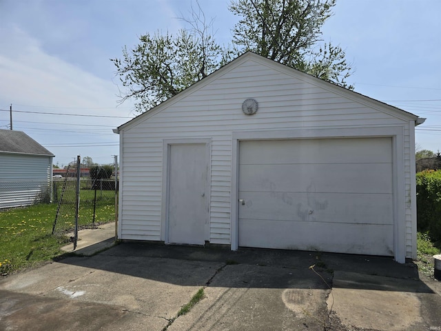 detached garage featuring fence and driveway
