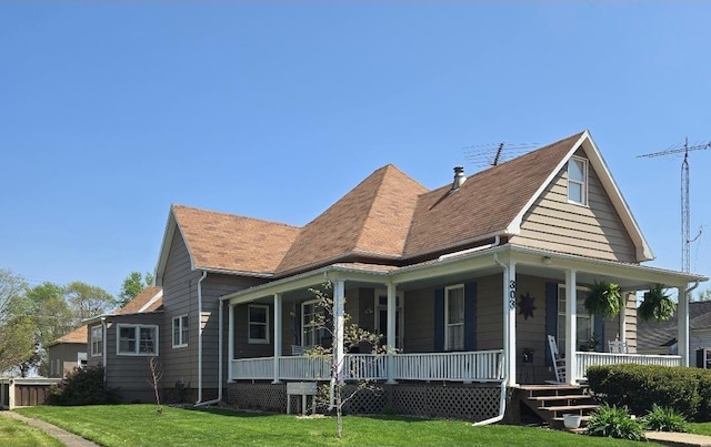 view of front of property featuring covered porch, a shingled roof, and a front lawn