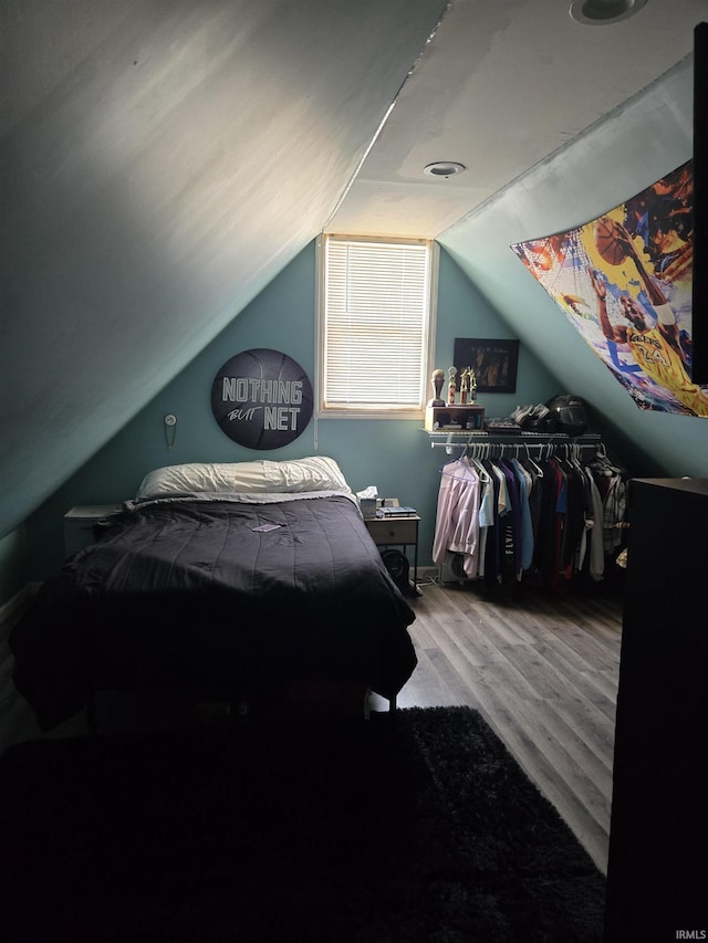 bedroom with wood finished floors and vaulted ceiling