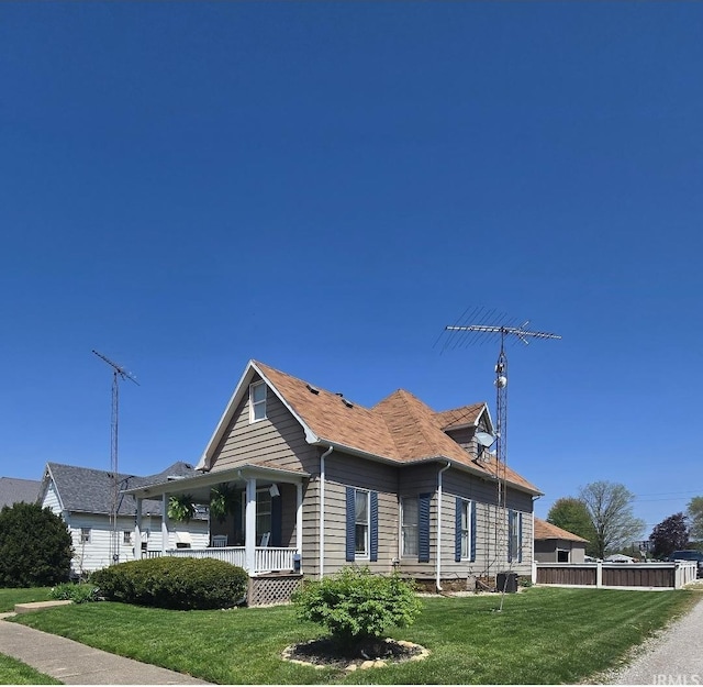 view of front of home with a porch, a front lawn, and fence