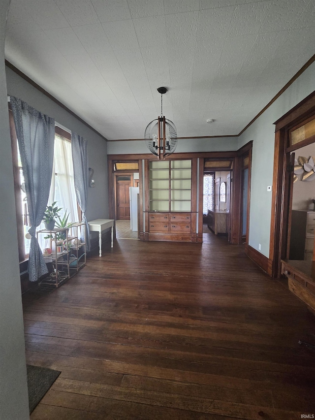 unfurnished dining area featuring crown molding, baseboards, wood-type flooring, and a notable chandelier