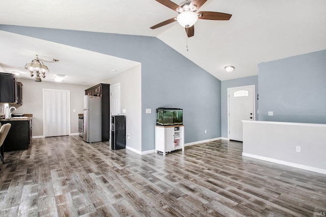 living area featuring wood finished floors, baseboards, ceiling fan with notable chandelier, and lofted ceiling
