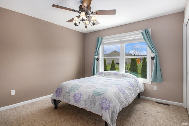 carpeted bedroom featuring visible vents, a ceiling fan, and baseboards
