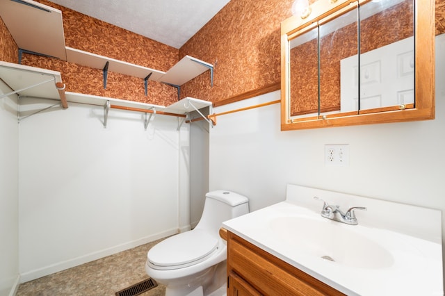 208 E Hickory Grove Rd, Hartford City, IN 47348 - bathroom with a walk in closet, vanity, toilet, baseboards, and visible vents