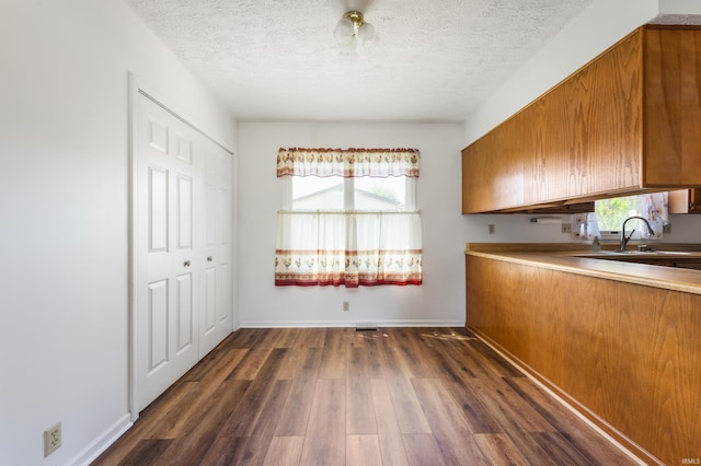 208 E Hickory Grove Rd, Hartford City, IN 47348 - kitchen with brown cabinets, dark wood-style flooring, a sink, light countertops, and a textured ceiling