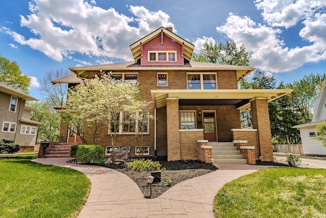 traditional style home featuring covered porch, a front lawn, and brick siding
