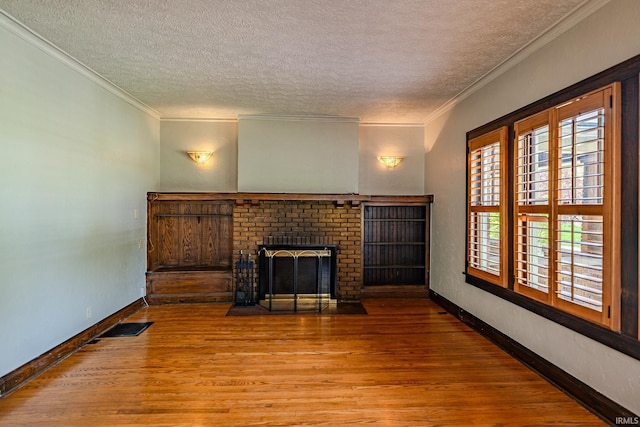 unfurnished living room featuring baseboards, a textured ceiling, a brick fireplace, and wood finished floors