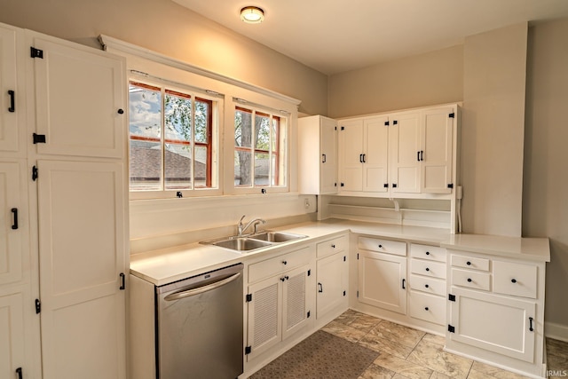 kitchen featuring stainless steel dishwasher, a sink, white cabinetry, and light countertops