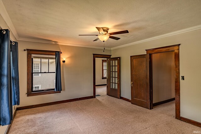 empty room featuring crown molding, a ceiling fan, baseboards, and light colored carpet