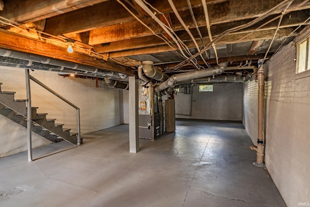 basement featuring stairway, heating unit, and a wealth of natural light