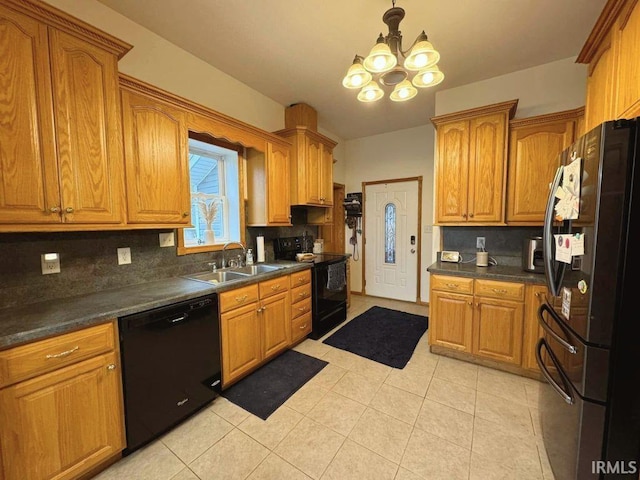 kitchen with dark countertops, black appliances, a sink, backsplash, and a notable chandelier