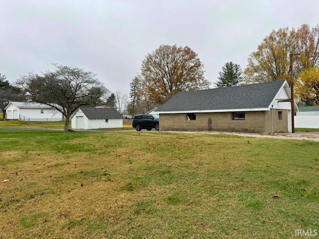 view of side of property with a detached garage, an outdoor structure, a yard, and concrete block siding